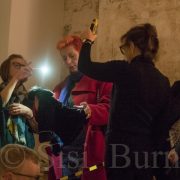 Theresa Albor holding up a torch to allow the audience to read during the performance at the opening of The Things we Leave Behind